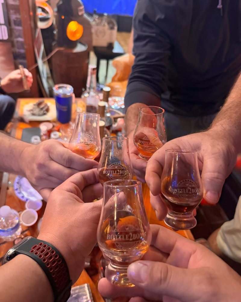 Friends toasting with Bottle2Bond travel whiskey glasses at a bottle share