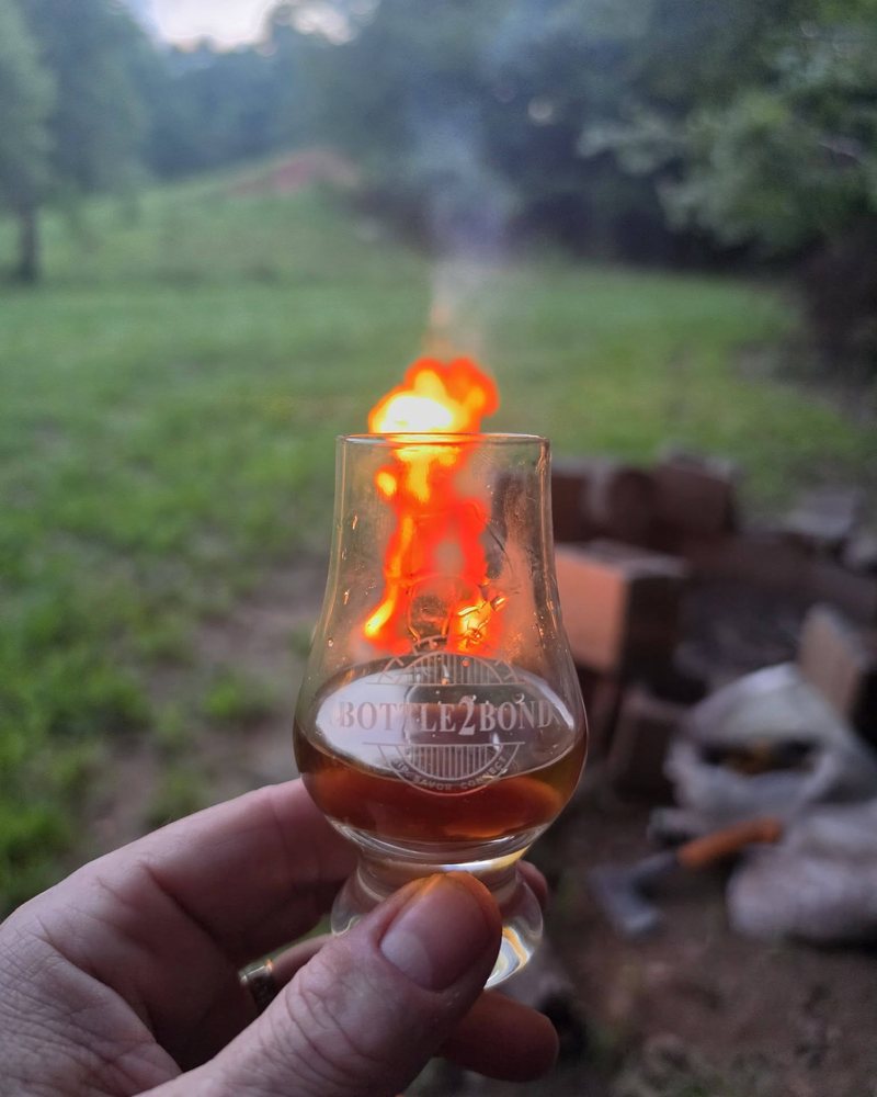 Bottle2Bond glass held in front of a campfire